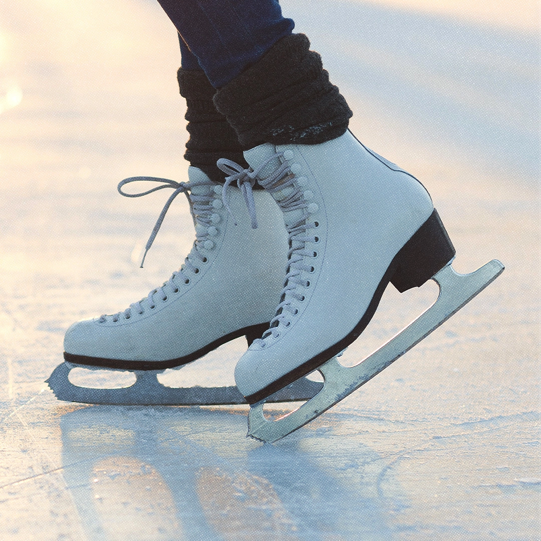 Close-up of white figure skates on the ice at an outdoor skating rink.