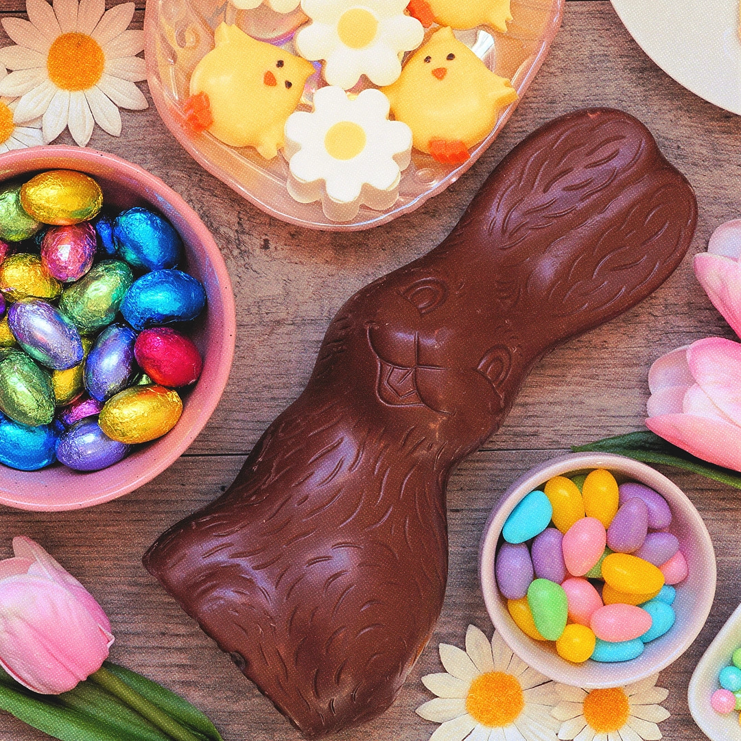 Lapin en chocolat et petits plats pleins d'oeufs en chocolat enveloppés de papiers multicolores.