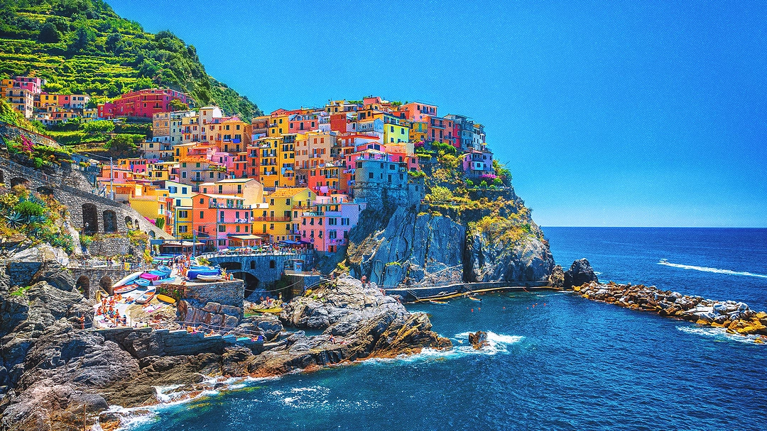 Village italien colloré au bord d'une falaise surplombant la mer.