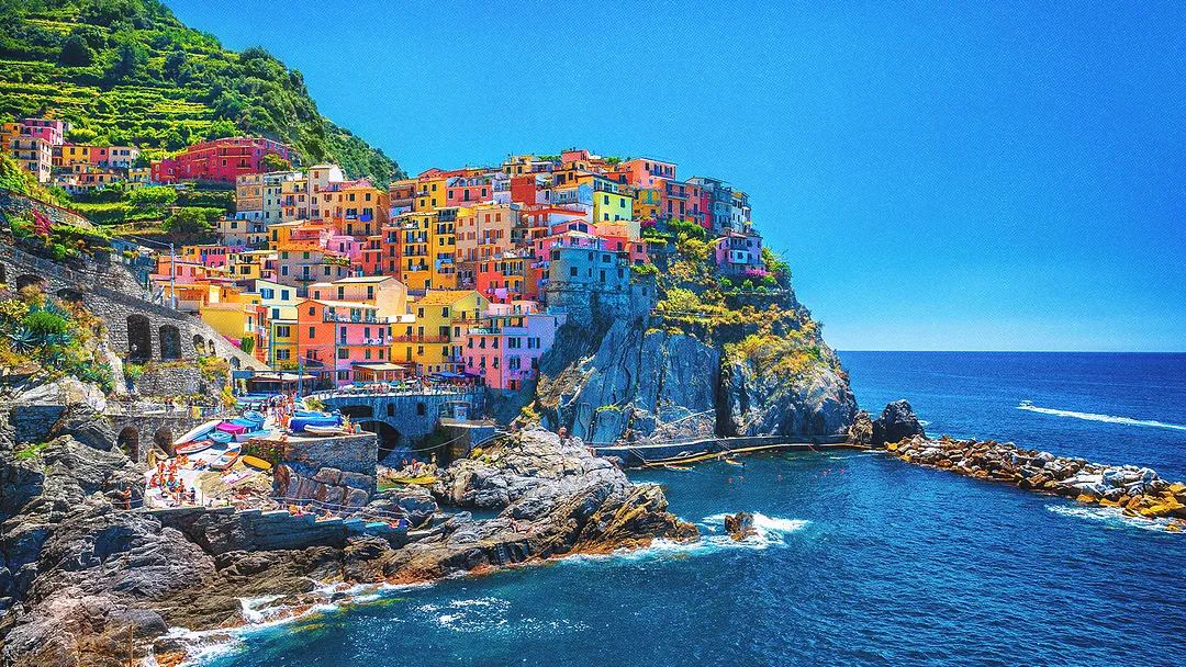 Village italien colloré au bord d'une falaise surplombant la mer.