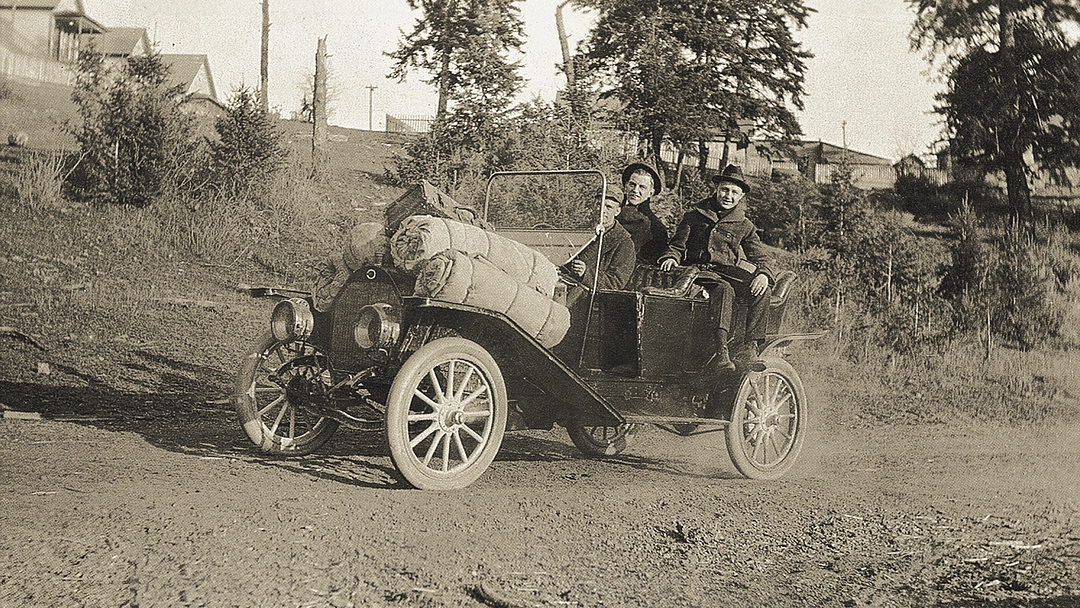 Photo historique en noir et blanc de deux personnes dans une voiture ancienne.