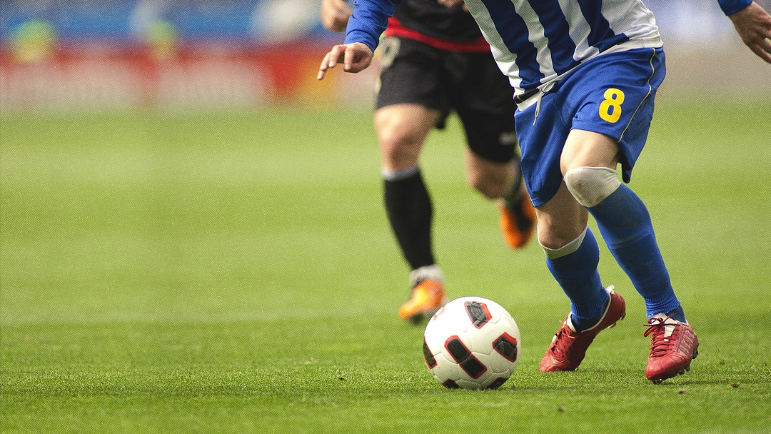 Deux joueurs se disputent un ballon de football.