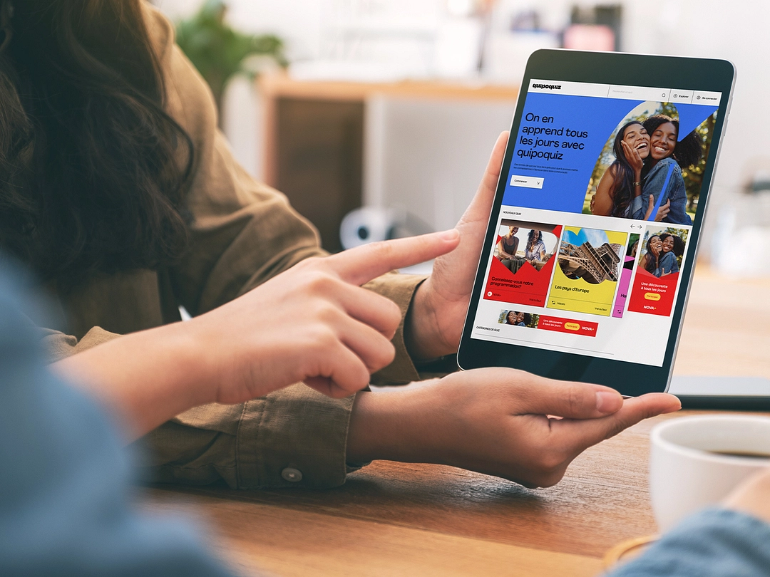 Personne tenant une tablette avec une page web de QuipoQuiz ouverte.